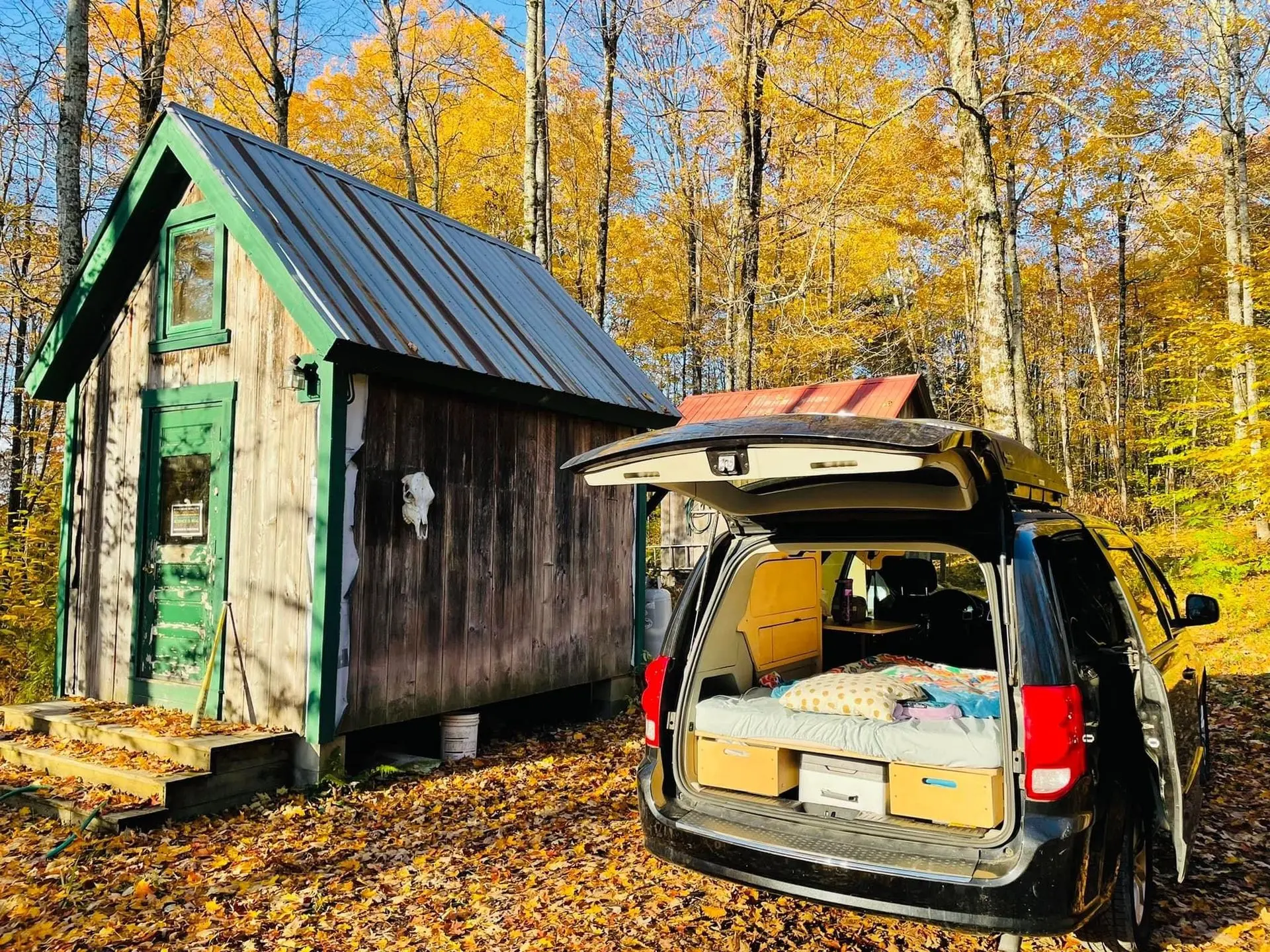 Dodge Grand Caravan avec un kit Lagom, hayon ouvert devant un chalet en automne