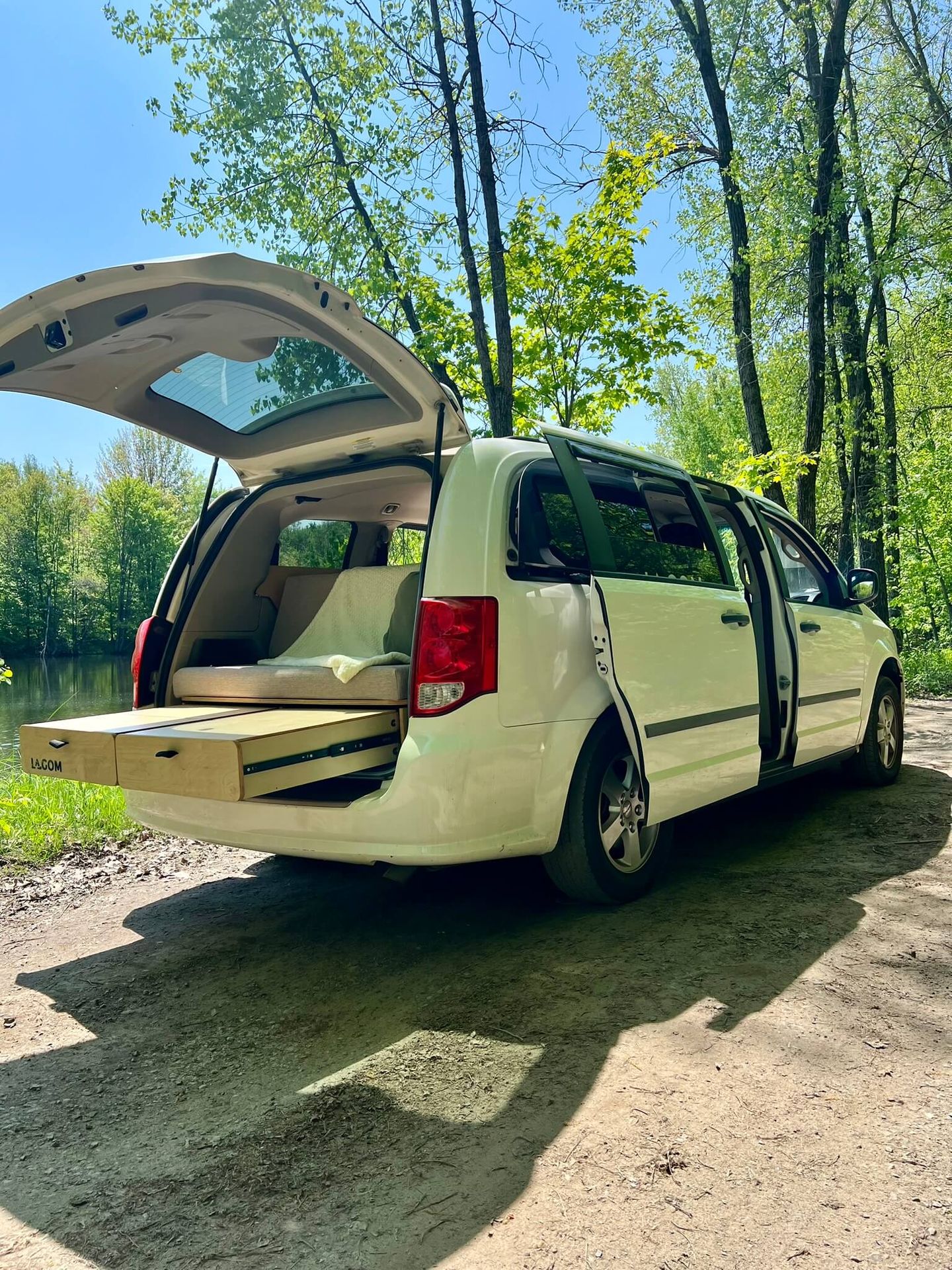 Dodge Grand Caravan blanche de profil, hayon ouvert et tiroir sorti