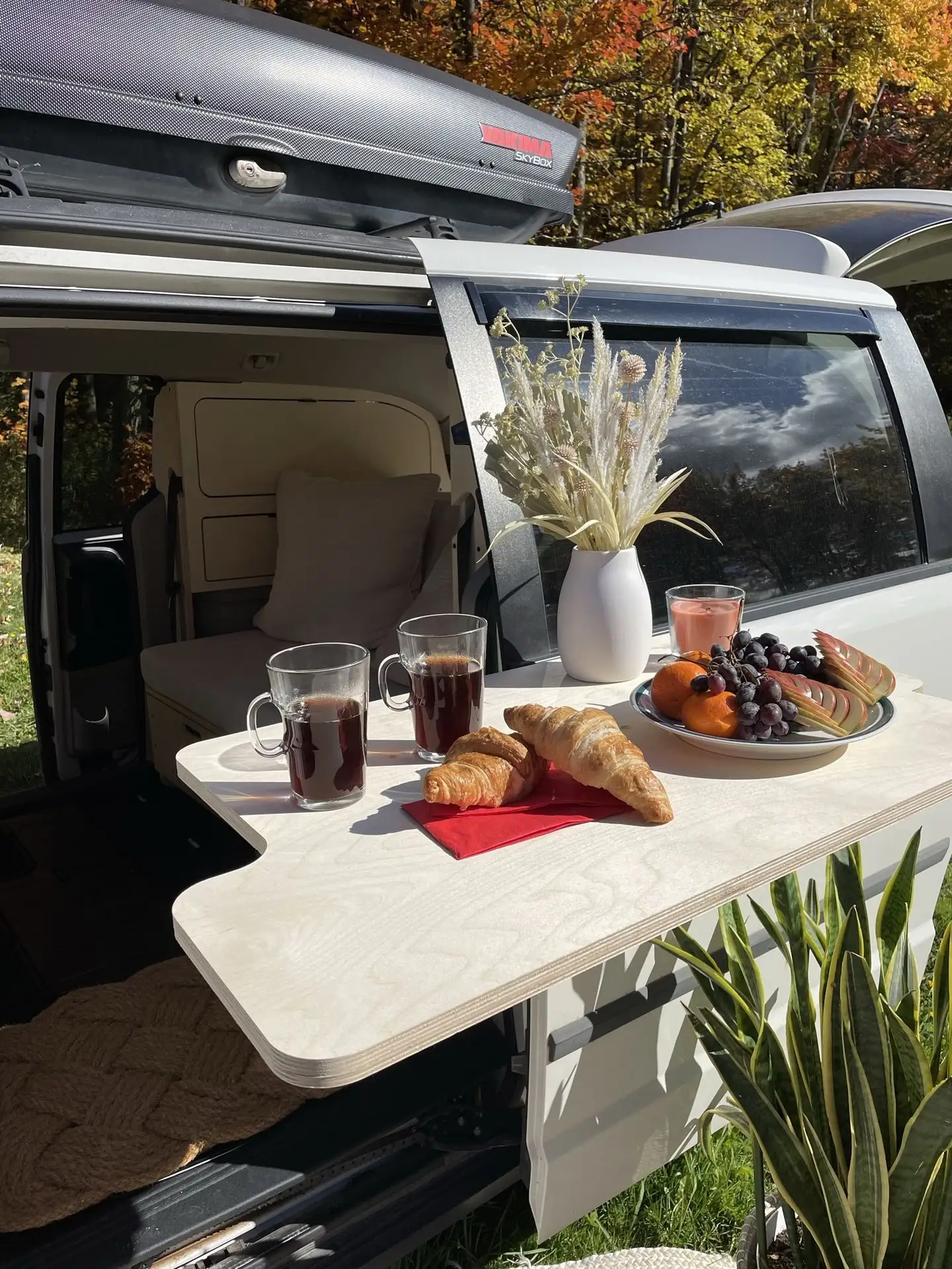 Petit déjeuner servi sur une table extérieure d’un minivan Lagom Conversion, parfait pour profiter de la nature.